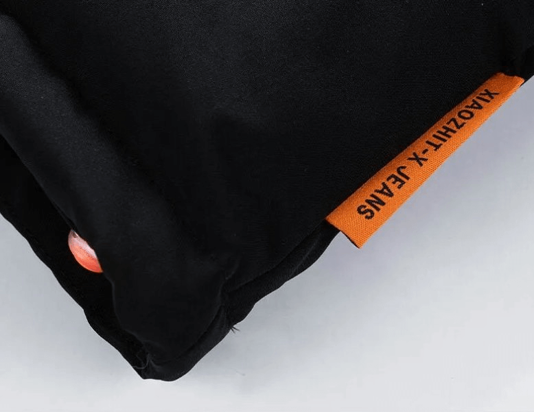 Close-up of black fabric with orange tag and text "XIAOZHI-T X-JEANS"